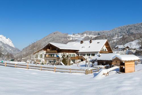a lodge in the snow with snow covered mountains at Gästehaus Pfeffererlehen in Marktschellenberg
