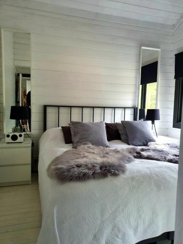a bedroom with a large white bed with a fur blanket at Villa Laiskajaakko in Vimpeli