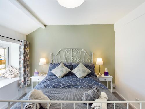 um quarto com uma cama azul e 2 almofadas em welsh country cottage in beautiful village em Llandudno Junction