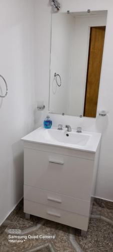 W łazience znajduje się biała umywalka i lustro. w obiekcie M&M l w mieście Comodoro Rivadavia