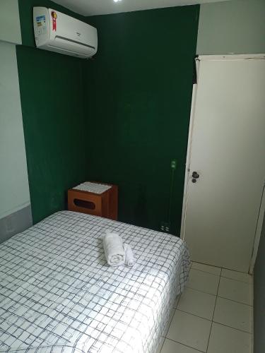a bedroom with a bed with a green wall at Quarto Familiar Aconchegante in Recife