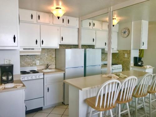 una cocina con electrodomésticos blancos y armarios blancos en Beachfront Bliss - Suite at Symphony Beach Club en Ormond Beach