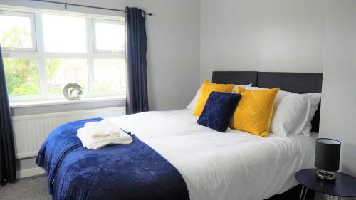 een slaapkamer met een groot bed met gele en blauwe kussens bij Spacious 3 bed house, great for FAMILIES and CONTRACTORS, sleeps 5 plus FREE Parking - Triumph Serviced Accommodation Wolverhampton in Wolverhampton