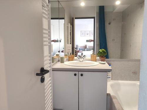La salle de bains blanche est pourvue d'un lavabo et d'une baignoire. dans l'établissement Joli Studio Tout Confort - Centre-ville, à Annecy
