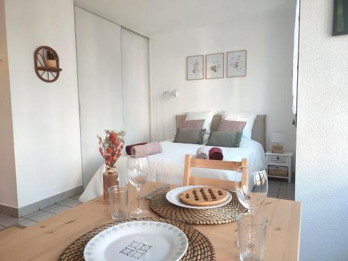 Cette chambre comprend un lit et une table avec des assiettes et des verres. dans l'établissement Joli Studio Tout Confort - Centre-ville, à Annecy
