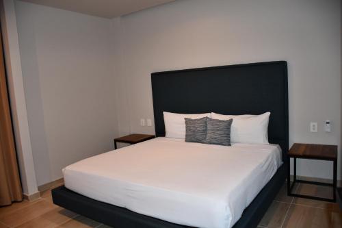 a bedroom with a white bed with a black headboard at Kaab At The Park by The Spot Rentals in Playa del Carmen