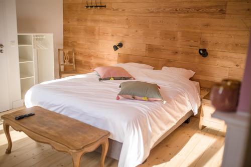 ein Schlafzimmer mit einem großen weißen Bett und einer Holzwand in der Unterkunft Le Mayou in Mortroux