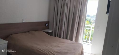 ein Schlafzimmer mit einem Bett und einem großen Fenster in der Unterkunft Bombinhas Summer Beach - Apto 303 in Bombinhas