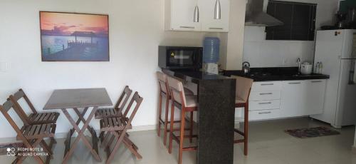 eine Küche mit einem Tisch, Stühlen und einer Mikrowelle in der Unterkunft Bombinhas Summer Beach - Apto 303 in Bombinhas