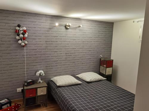 1 dormitorio con cama y pared de ladrillo en Très bel appartement avec vue sur les montagnes, en Saint-Ismier