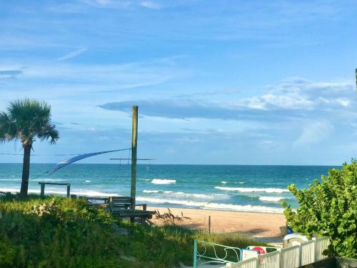 a beach with a palm tree and the ocean at Just Beachy -Ocean View at Symphony Beach Club in Ormond Beach