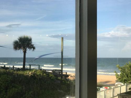 a view of a beach with a palm tree and the ocean at Just Beachy -Ocean View at Symphony Beach Club in Ormond Beach