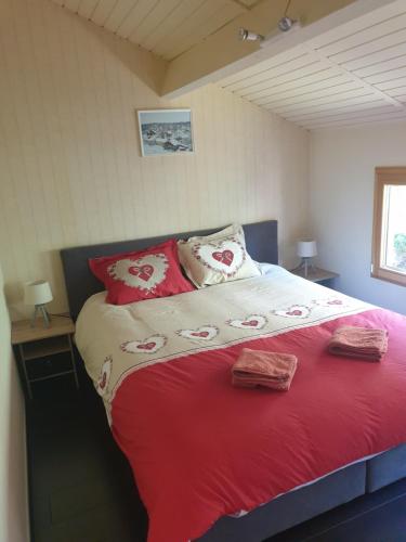 Duplex de charme avec terrasse في Les Hôpitaux-Neufs: غرفة نوم بسرير ذو شراشف ومخدات حمراء