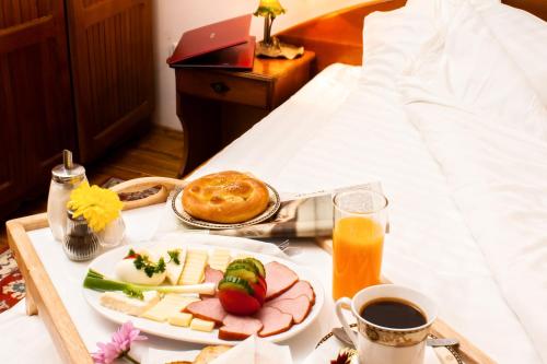 Una bandeja de desayuno con queso y fruta sobre una cama. en Pensiunea Boema, en Sinaia