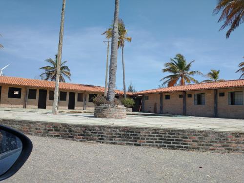 a building with palm trees and a brick wall at Porto Canoa, Chios Ap 102 , Aracati, CE in Aracati