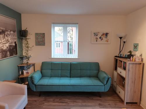 Sofá azul en la sala de estar con ventana en Cosy Apartment with Balcony en Herne Bay