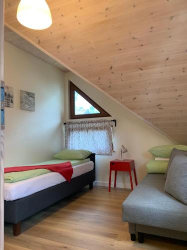 ein Schlafzimmer mit einem Bett, einem Fenster und einem Sofa in der Unterkunft Na Wczasowej in Międzywodzie