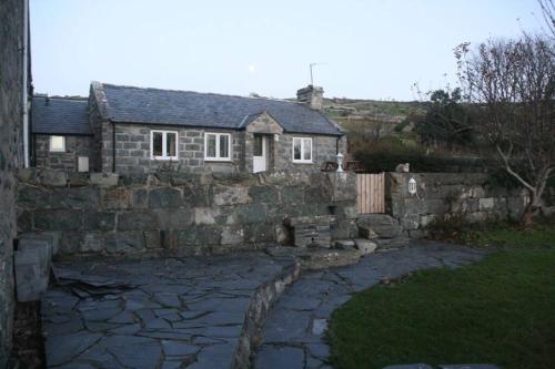 a stone house with a stone wall at Hendre Fechan Cottage, Nr Barmouth, Pets welcome, beautiful views. in Llanddwywe