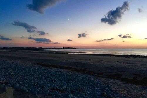 a sunset on a beach with the ocean at Hendre Fechan Cottage, Nr Barmouth, Pets welcome, beautiful views. in Llanddwywe