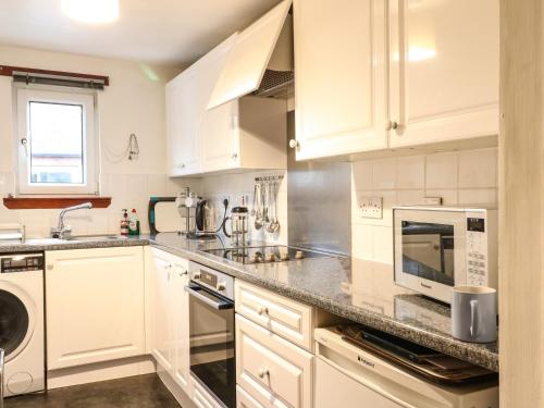 a kitchen with white cabinets and a sink and a microwave at Aberfoyle Apartment in Aberfoyle