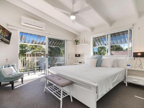 a white bedroom with a large bed and a chair at Belli Street 3 in Noosa Heads
