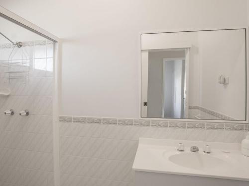 a white bathroom with a sink and a mirror at Summer Beach House in Kioloa