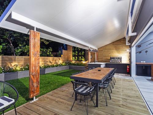 an outdoor patio with a wooden table and chairs at La Luna Shoal Bay 30 Horace St Shoal Bay in Shoal Bay
