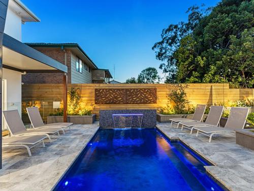a swimming pool with chairs and a fireplace in a backyard at La Luna Shoal Bay 30 Horace St Shoal Bay in Shoal Bay