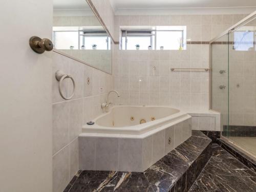 a white bathroom with a tub and a shower at Laman Lodge Unit 5 15 Laman Street in Nelson Bay