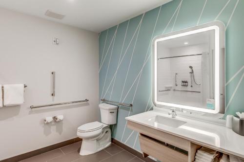 a bathroom with a toilet and a sink and a mirror at avid hotels - Zeeland by IHG in Holland