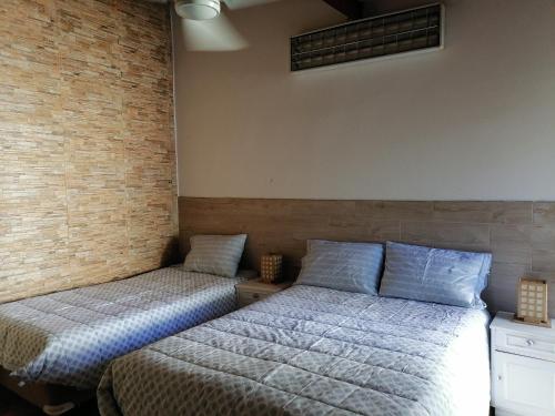 2 camas en una habitación con una pared de ladrillo en Granados, en Asunción