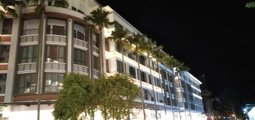 a tall building with palm trees in front of it at PINTARMAN FAMILY SUITES @ MIRI TIMES SQUARE in Miri