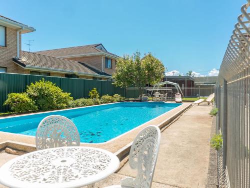 a pool with a table and chairs next to a fence at Tamara Court in Sawtell