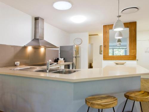 a kitchen with a sink and two stools at Park Cove 4 Park Road 48 in Noosa Heads