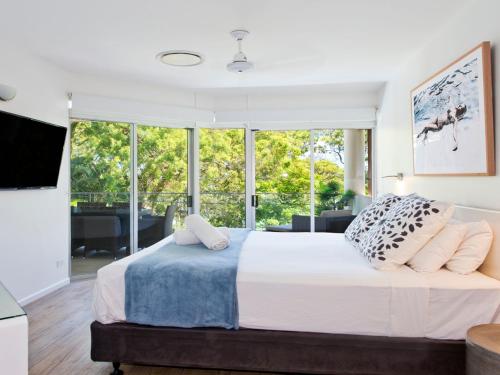 een slaapkamer met een bed en een groot raam bij Park Cove 4 Park Road 48 in Noosa Heads