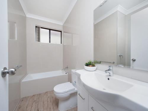 a white bathroom with a sink and a toilet at Bay Village Unit 6 47 Shoal Bay Road in Shoal Bay