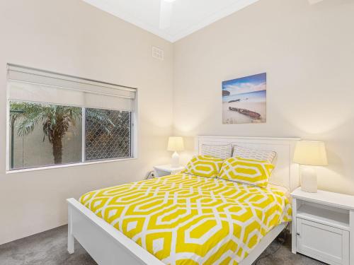 a bedroom with a yellow and white bed and a window at Bayview Towers Unit 13 Victoria Parade 15 in Nelson Bay