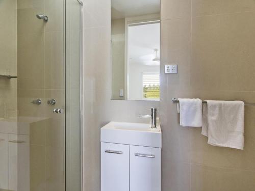 a bathroom with a sink and a shower with a mirror at Weyba Quays Townhouse 7 Peza Court 6 in Noosa Heads