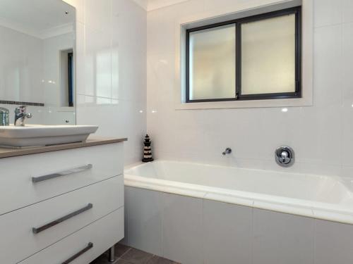een witte badkamer met een bad en een wastafel bij Beach House 1 20 Pacific Drive in Fingal Bay