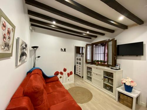 sala de estar con sofá rojo y TV de pantalla plana en Don Quijote, en Toledo