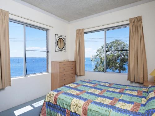 a bedroom with a bed and two large windows at Bella Vista Unit 3 19 Shoal Bay Road in Shoal Bay