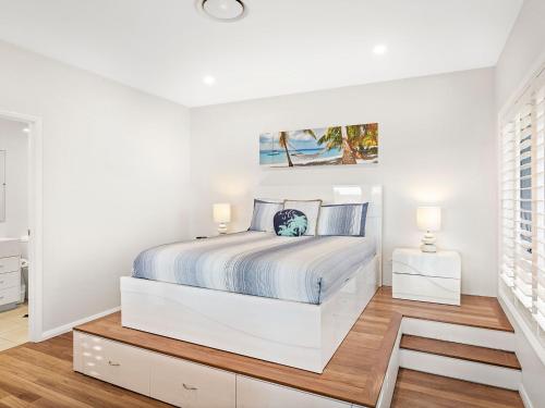 a white bedroom with a bed and two lamps at Boulder Bay Rd 1 2 Fingal Bay in Fingal Bay