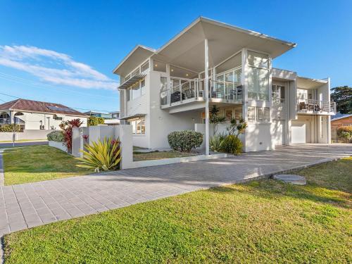 una gran casa blanca con un camino delante de ella en serenity at Fingal Bay 1, en Fingal Bay