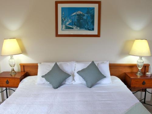 een slaapkamer met een wit bed en 2 lampen bij Breakwater 102 Shoal Bay in Shoal Bay