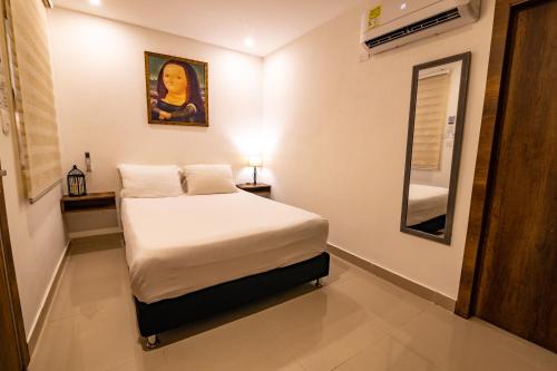 a small bedroom with a bed and a mirror at Hotel Amoek in Cartagena de Indias