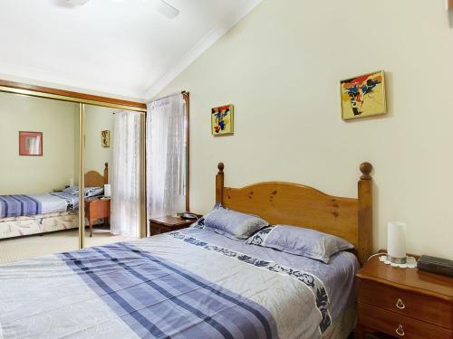 - une chambre avec un grand lit et un miroir dans l'établissement Macadamia Court 2 8 Government Road, à Nelson Bay