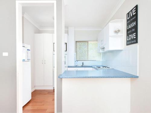 a kitchen with white cabinets and a blue counter top at Mistral Court Unit 16 17 Mistral Close in Nelson Bay