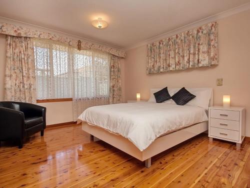 a bedroom with a bed and a chair and windows at Nelson Street 19 in Nelson Bay