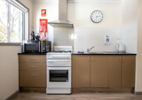 a kitchen with a stove and a clock on the wall at Snow Gum Apartment 2 in Baw Baw Village