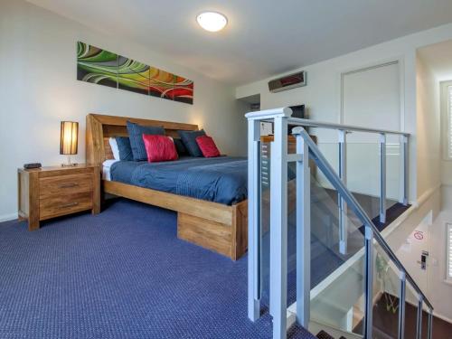 a bedroom with a bed and a staircase at Pacific Blue Apartment 139, 265 Sandy Point Road in Salamander Bay